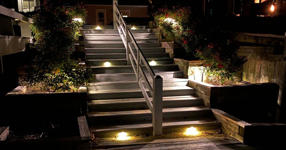 A residential property with landscape lighting installed in the walkway and patio.