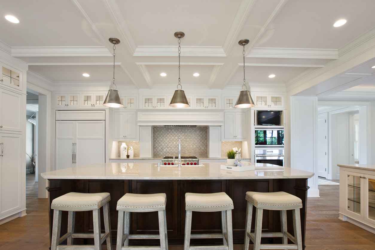 White kitchen with brown island and pendant lighting