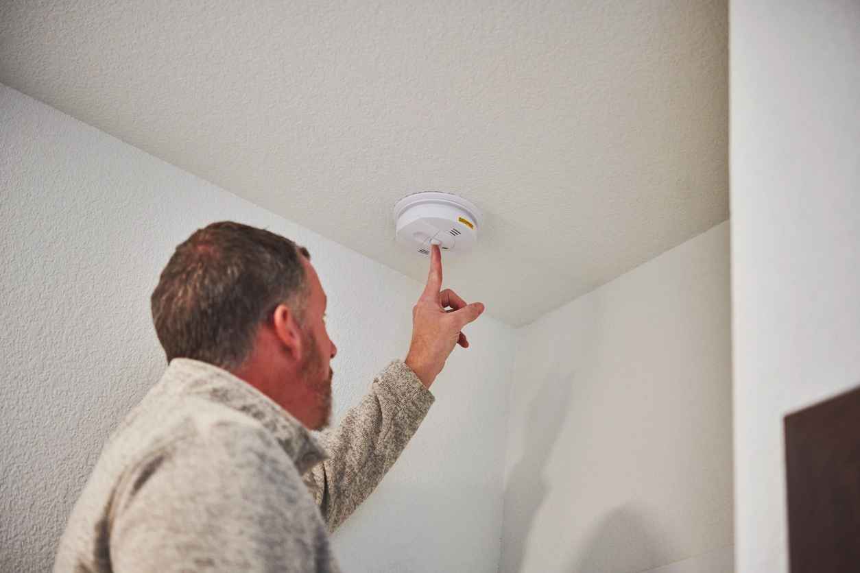 Male home inspector checking the working condition of a smoke and carbon monoxide detector during the home inspection of a residential property