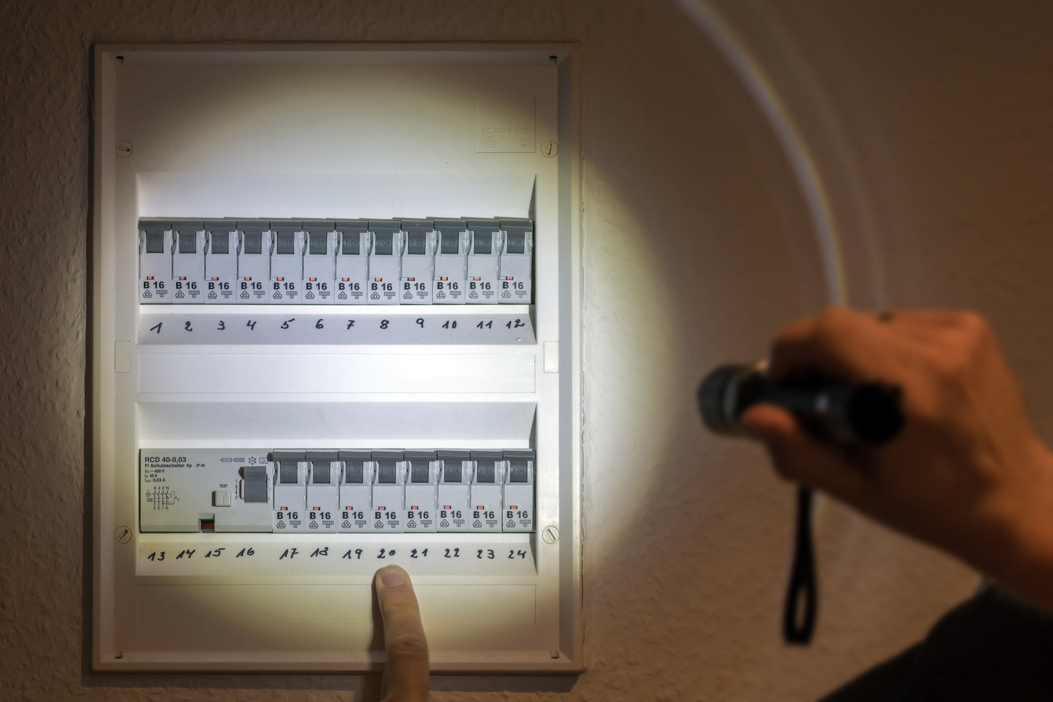 Electrician Shining Flashlight on Fuse Box