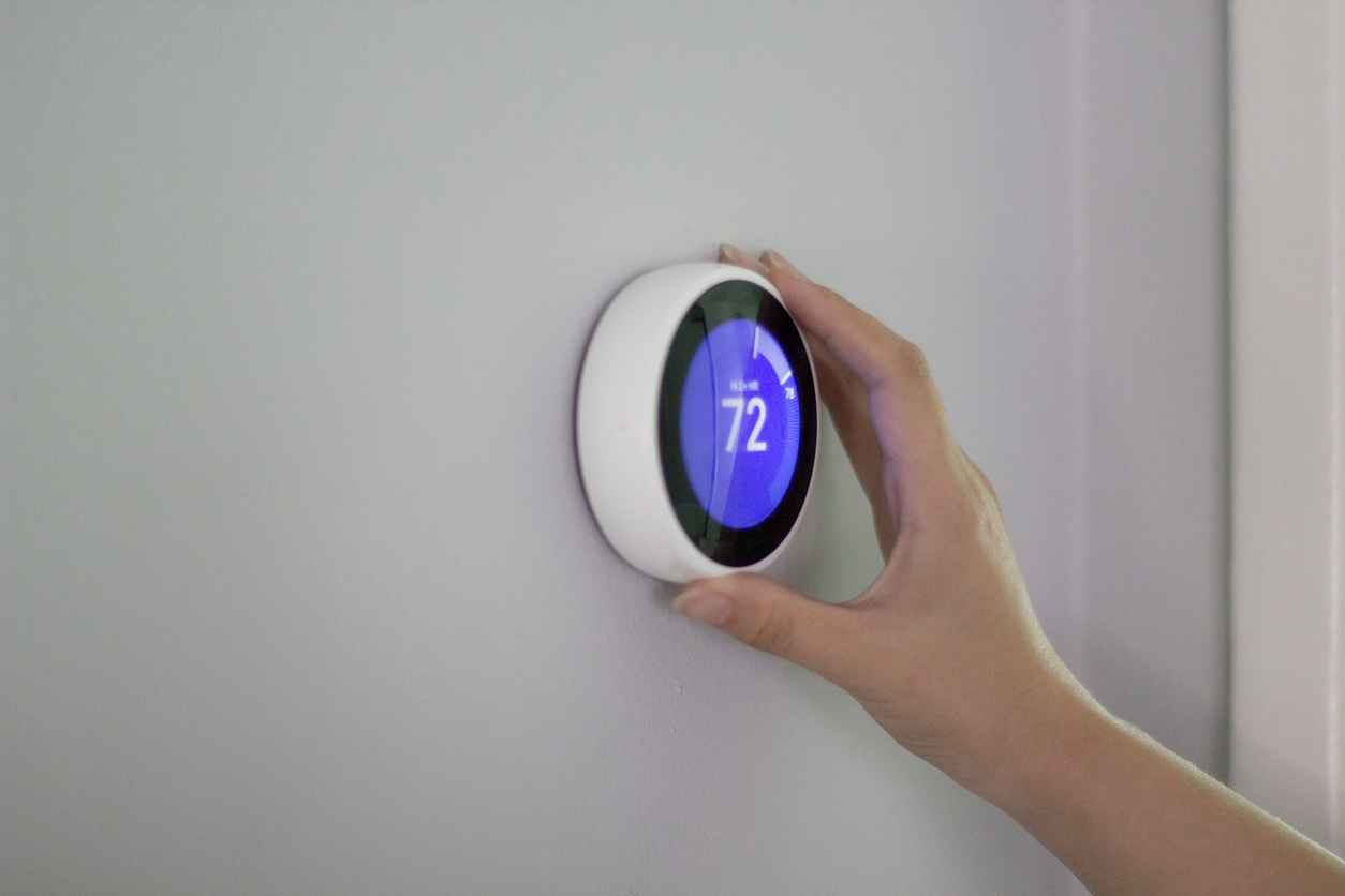 Homeowner adjusting smart thermostat on wall