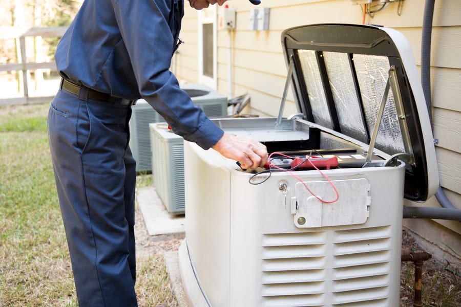 Certified generator specialist performing maintenance on a whole-home standby generator installed outside a Maryland residence.