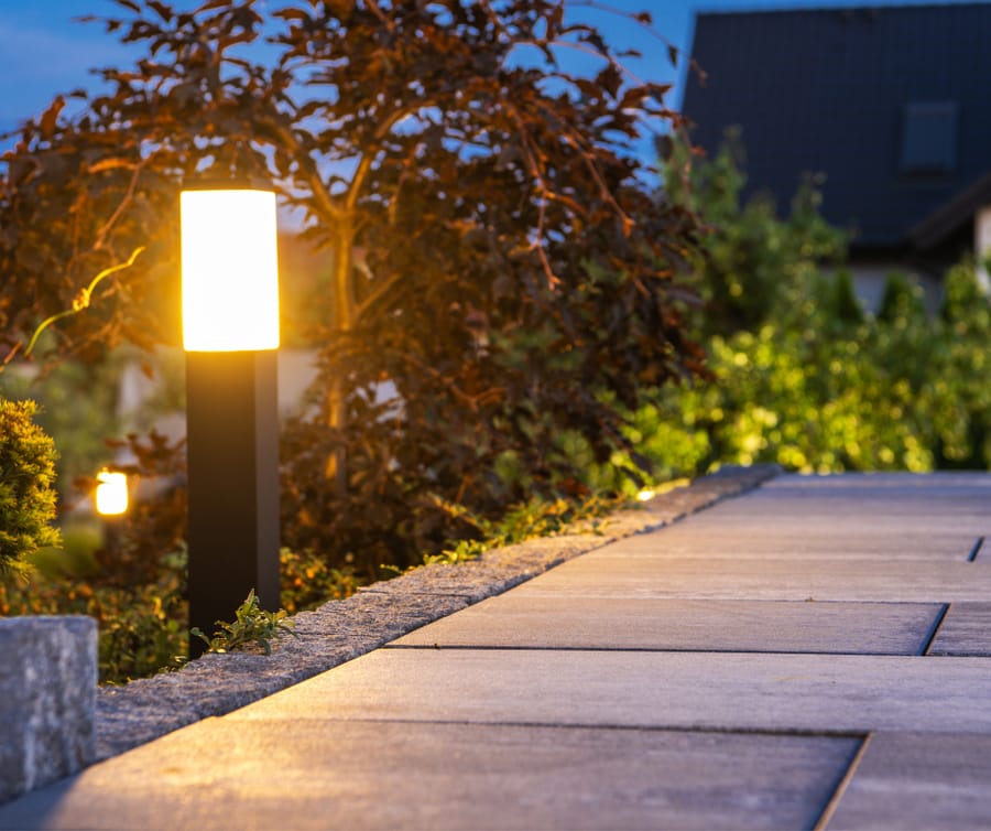 Lighted pathway leading up to a home. Landscape lighting offering light and security outside of a home
