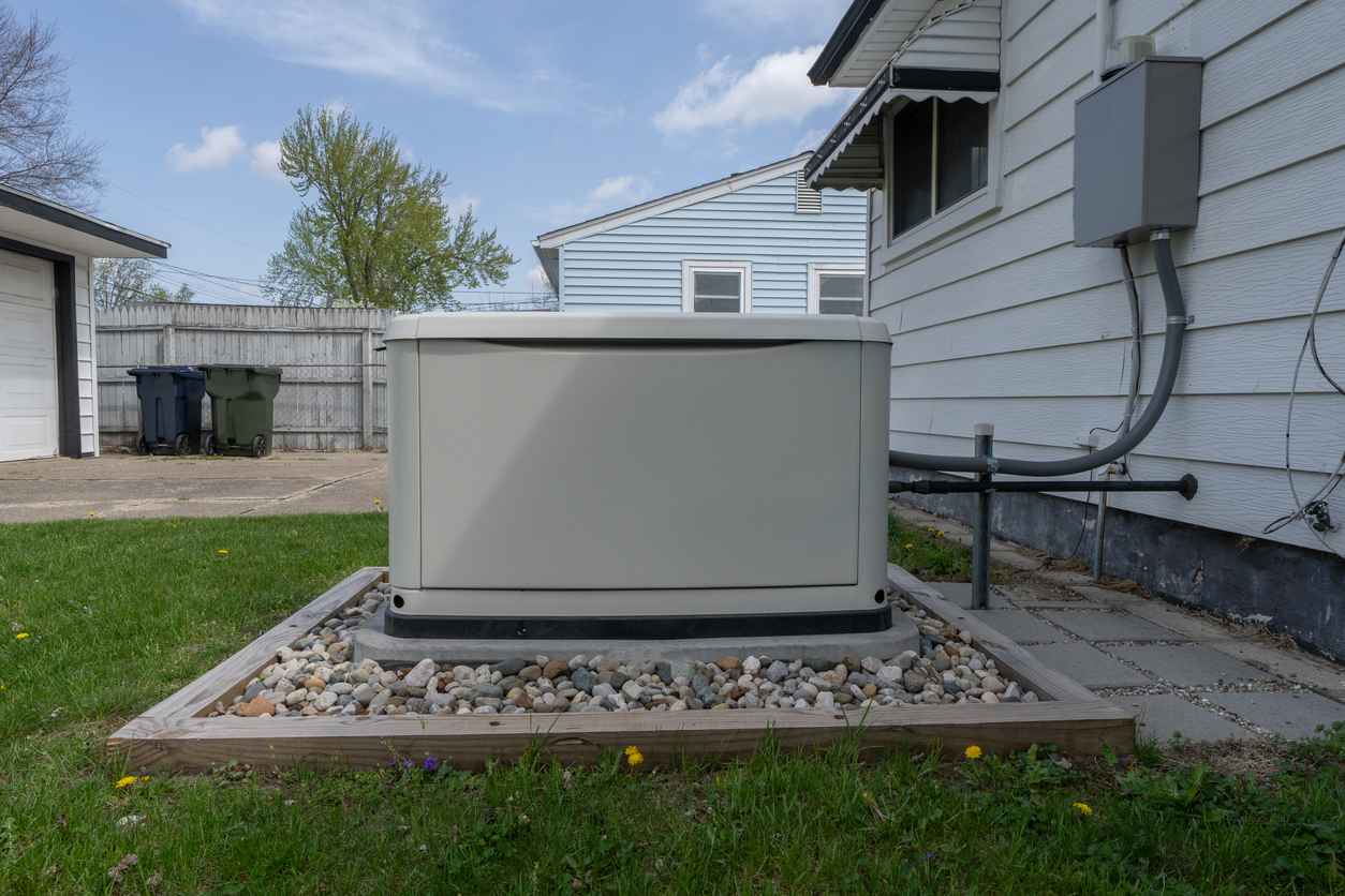 A generator in backyard of home on concrete slab surrounded by stones