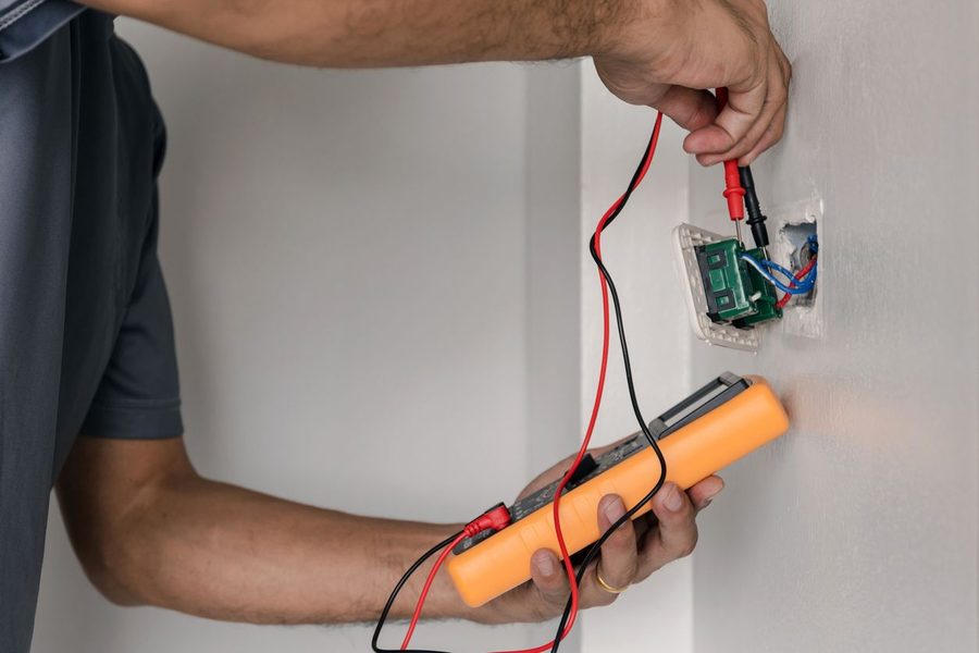 Electrician repairing an outlet on the wall