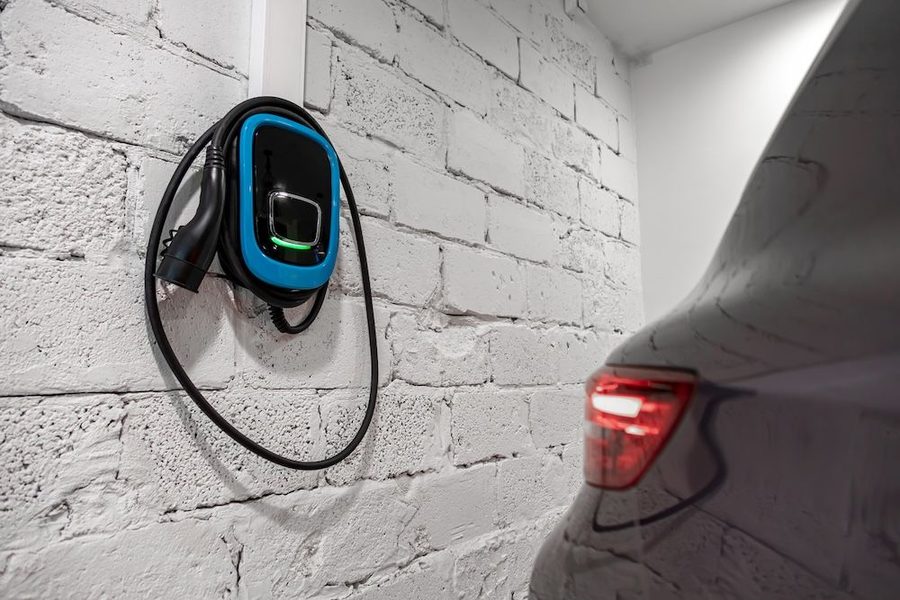 EV charger installed on garage wall with car parked next to it.