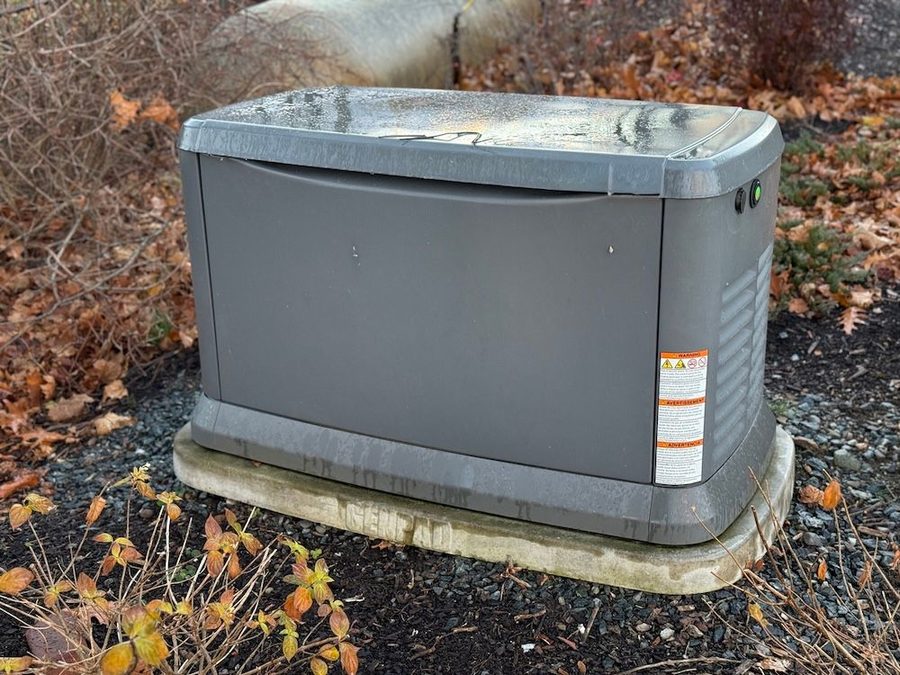 Generator outside on a concrete slab with mulch and leaves surrounding it