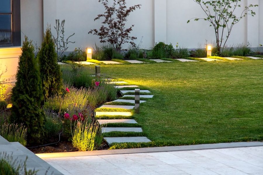 Walkway outside of a home that is lit with landscape lighting